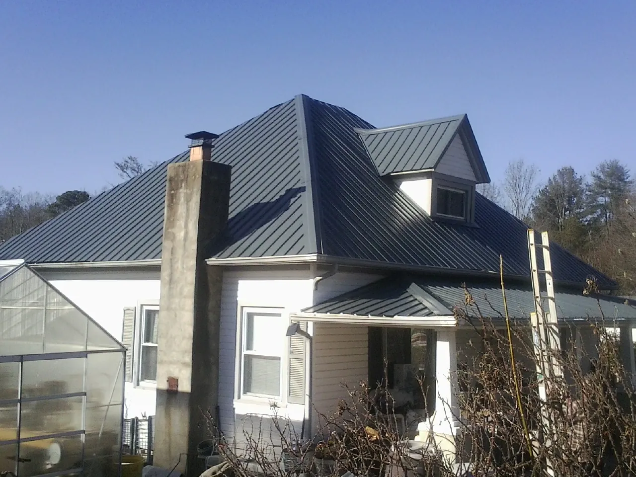 Dark blue standing seam metal roof on a white farmhouse with dormer — Slate & Tile Roof Repair by Roofing Brothers in Mize