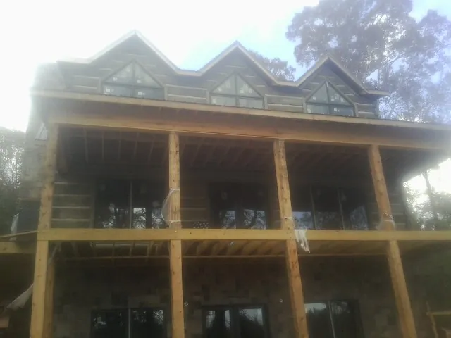 Dormers and porch framing on a large log home under construction — Roof Coating work by our crew in Mize